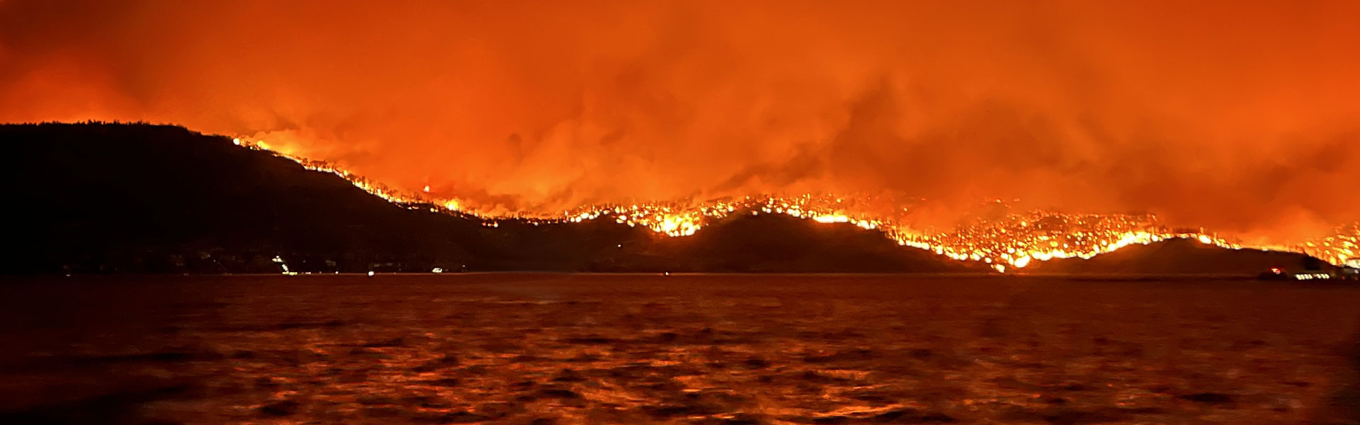 Looking at a wildfire spreading across the horizon from the otherside of Okanagan Lake at night.