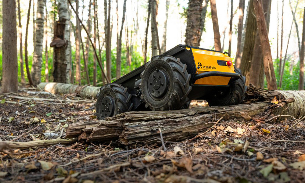 A Husky A300 rugged mobile robot unit works it's way over a forest floor and tree debris